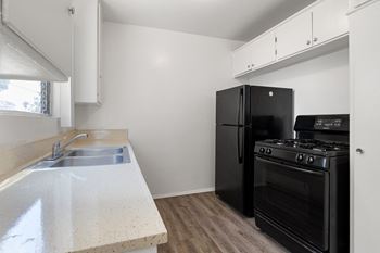 an empty kitchen with black appliances and white counter tops